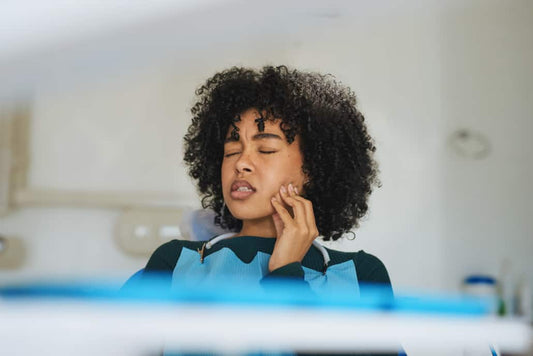 Shot of a young woman suffering from toothache while sitting in the dentist’s chair
